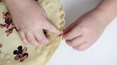 Fluting edge of pie with thumbs and forefinger