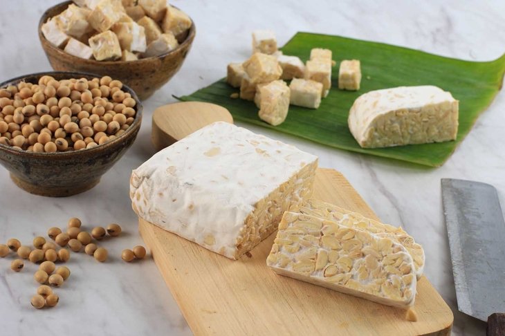 Raw Tempeh or Tempe. Tempeh Slices on Wooden Background, Cut by Asian Female Chef. Tempe Made From Fermented Soybeans. Copy Space for Text. Concept of Soy Product