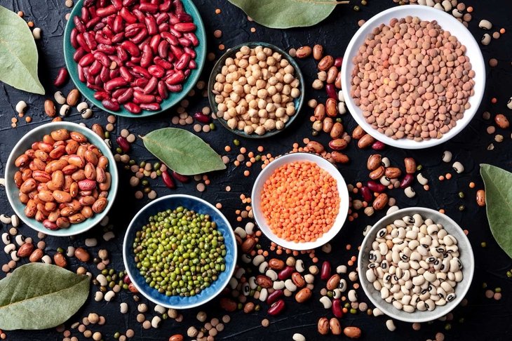 Legumes assortment, shot from the top on a black background. Lentils, soybeans, chickpeas, red kidney beans, a vatiety of pulses