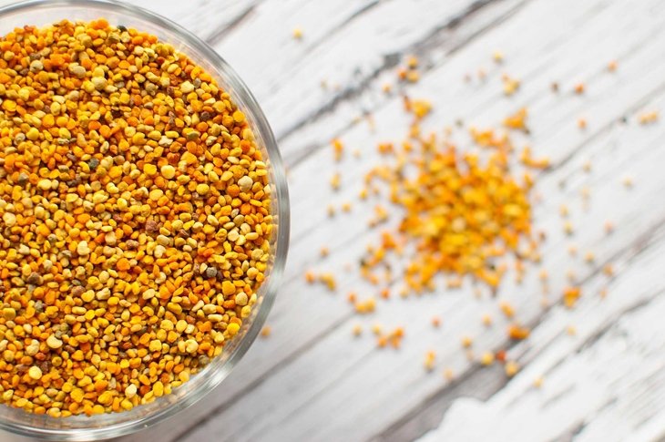 raw organic bee pollen over wooden board