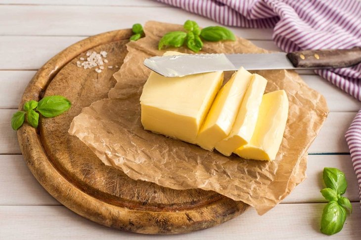 Butter. Slice of butter. Fresh sliced butter on the wooden plate.